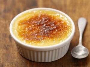 Assorted flavored crème brûlées with garnishes on a marble countertop