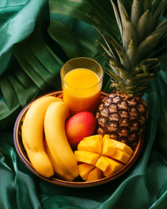 A tropical fruit bowl with banana, mango, papaya, and pineapple juice