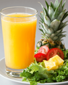 Pineapple juice next to a fresh salad, symbolizing digestive benefits