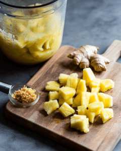 Ingredients for a ginger and pineapple recipe on a cutting board.